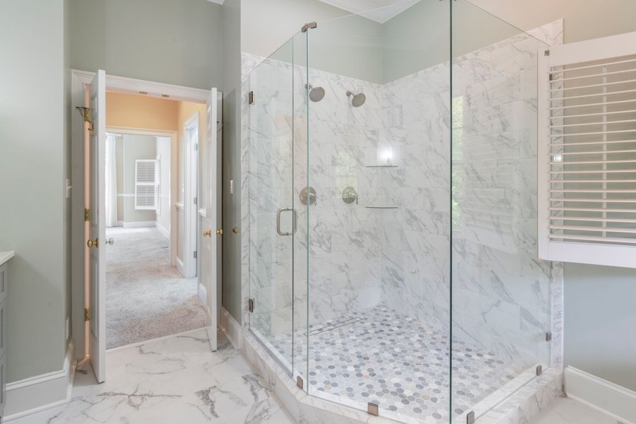 Renovated bathroom with a frameless glass shower, marble wall tile, and a mosaic tile shower floor