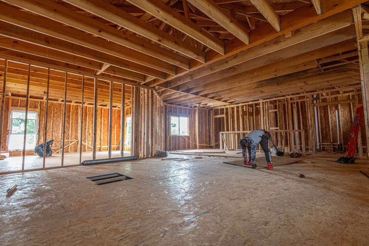 Interior of a single family home at the framing stage, with open stud walls and ceiling joists