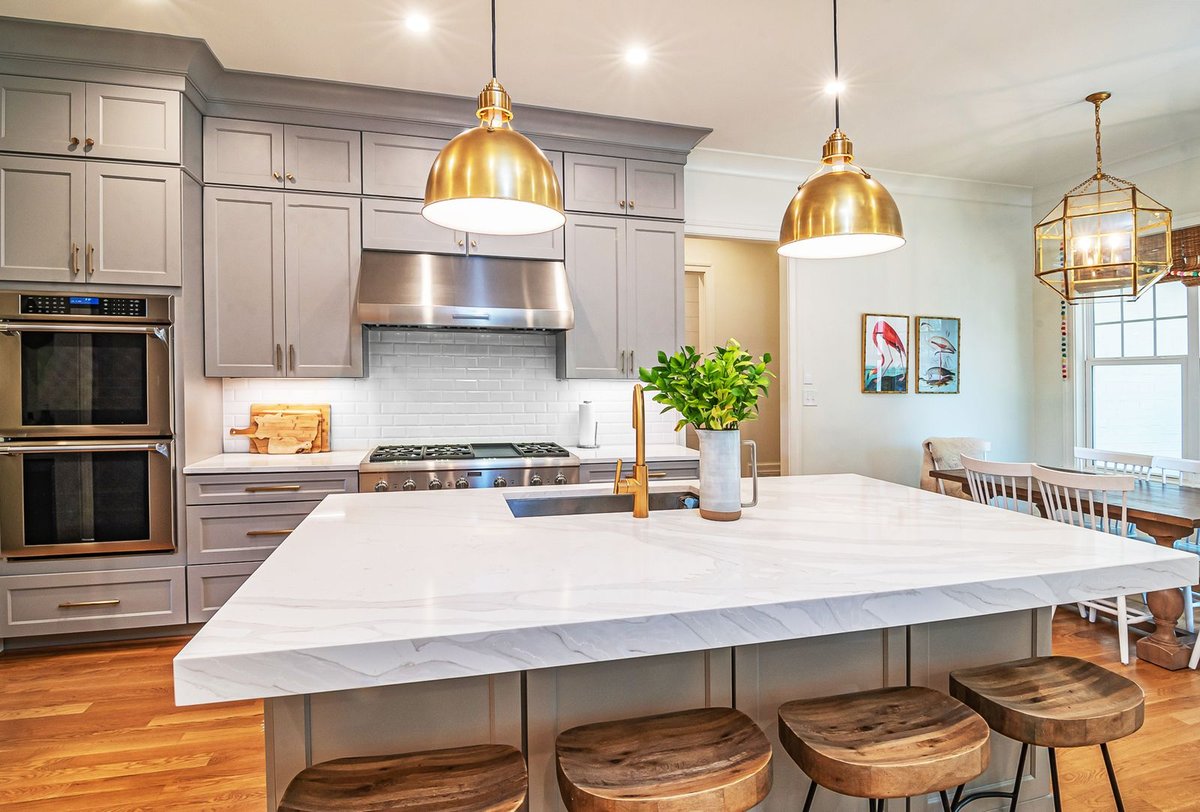 Modern kitchen with a large marble island, wood cabinetry, and pendant lighting