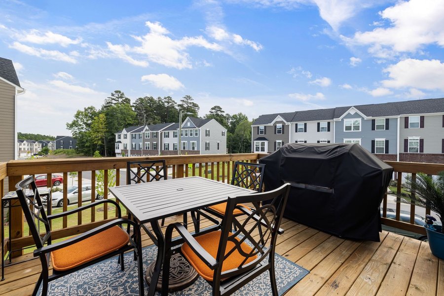 Wooden backyard deck with outdoor dining furniture and a grill
