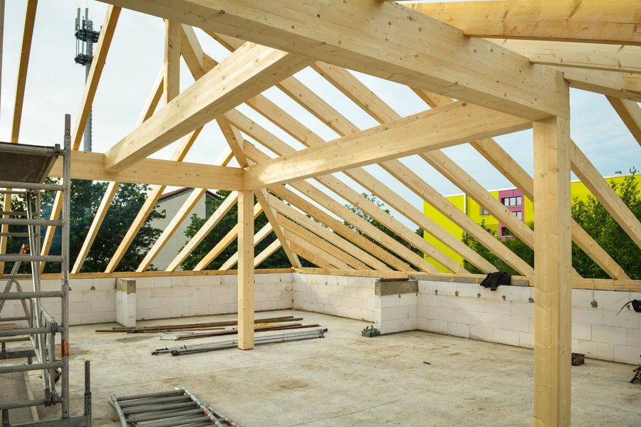 Wooden roof framing with exposed rafters and ridge beam under an open sky
